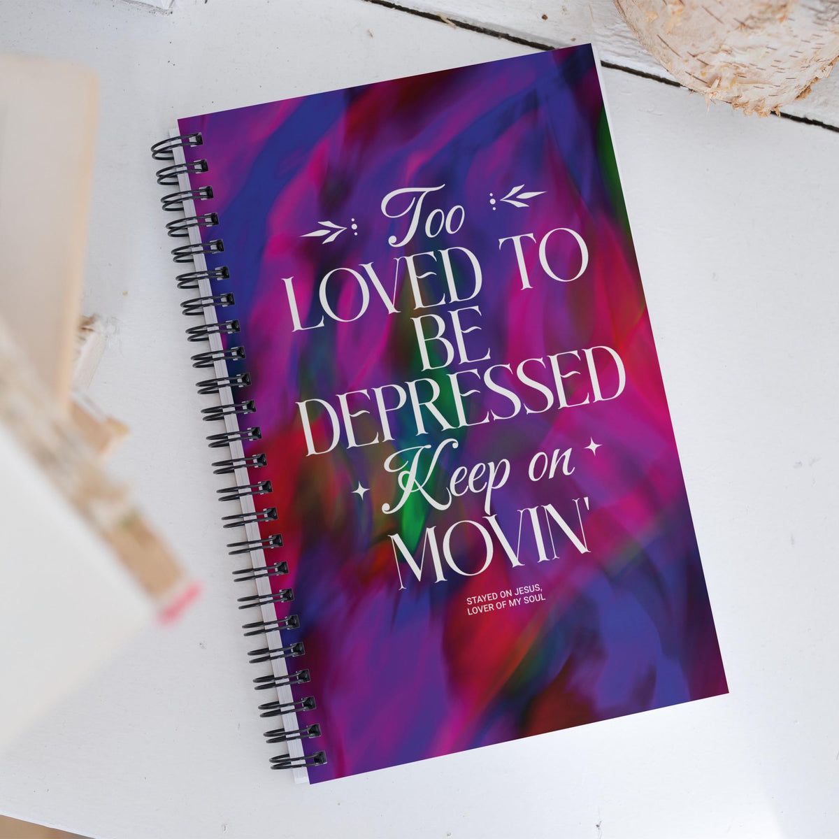 Too Loved to Be Depressed spiral notebook on a desk