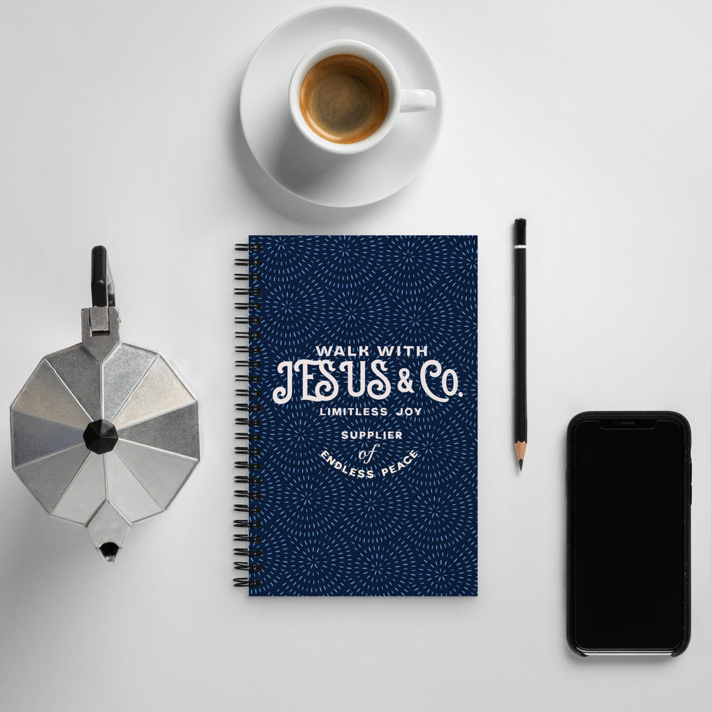Walk With Jesus & Co navy Christian spiral notebook on a desk with coffee